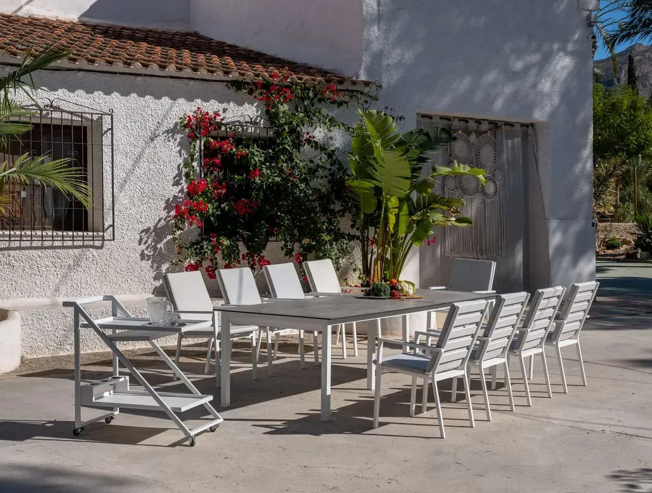 Un patio con una mesa y sillas frente a una casa blanca.