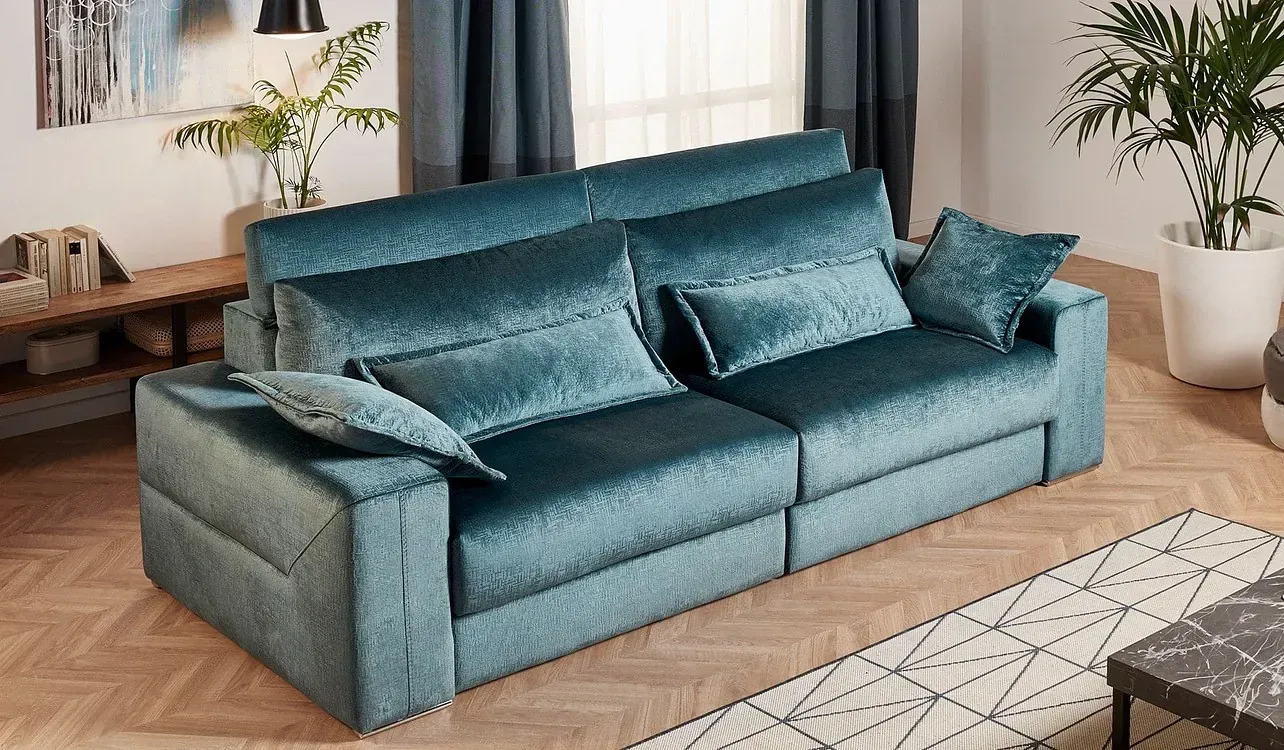 Un sofá azul está sentado sobre un piso de madera en una sala de estar.