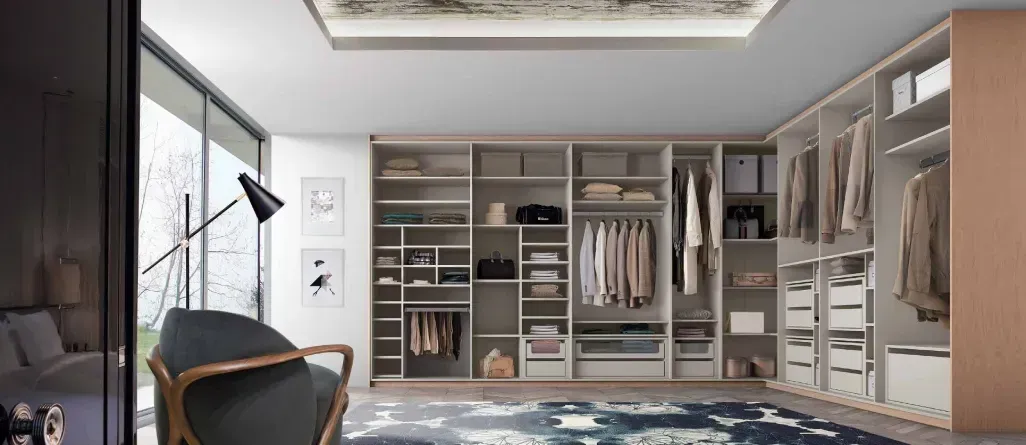 Un gran vestidor con mucha ropa y una silla.