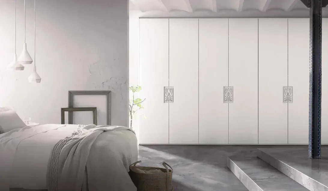 Un dormitorio con una cama, escaleras y armarios blancos.