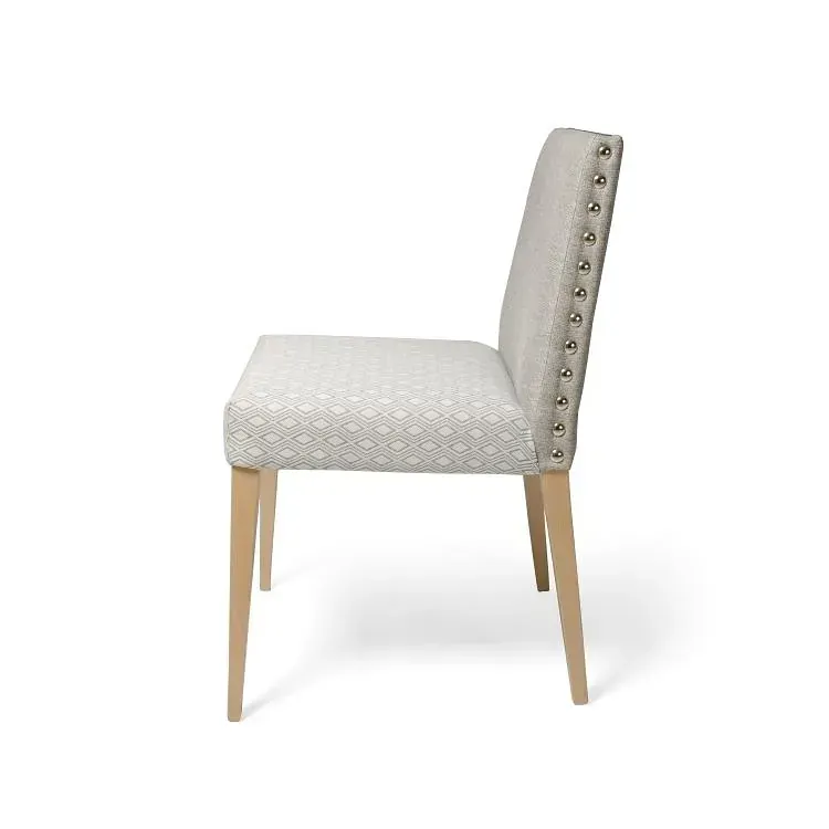 Una silla blanca con patas de madera y tachuelas en el respaldo sobre un fondo blanco.