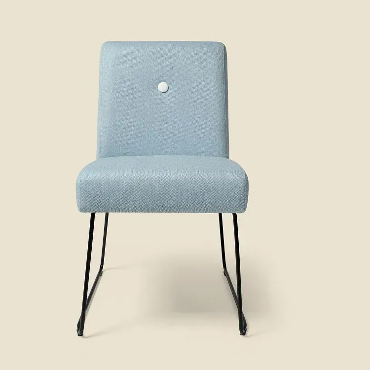 Una silla azul claro con un botón blanco en el respaldo.