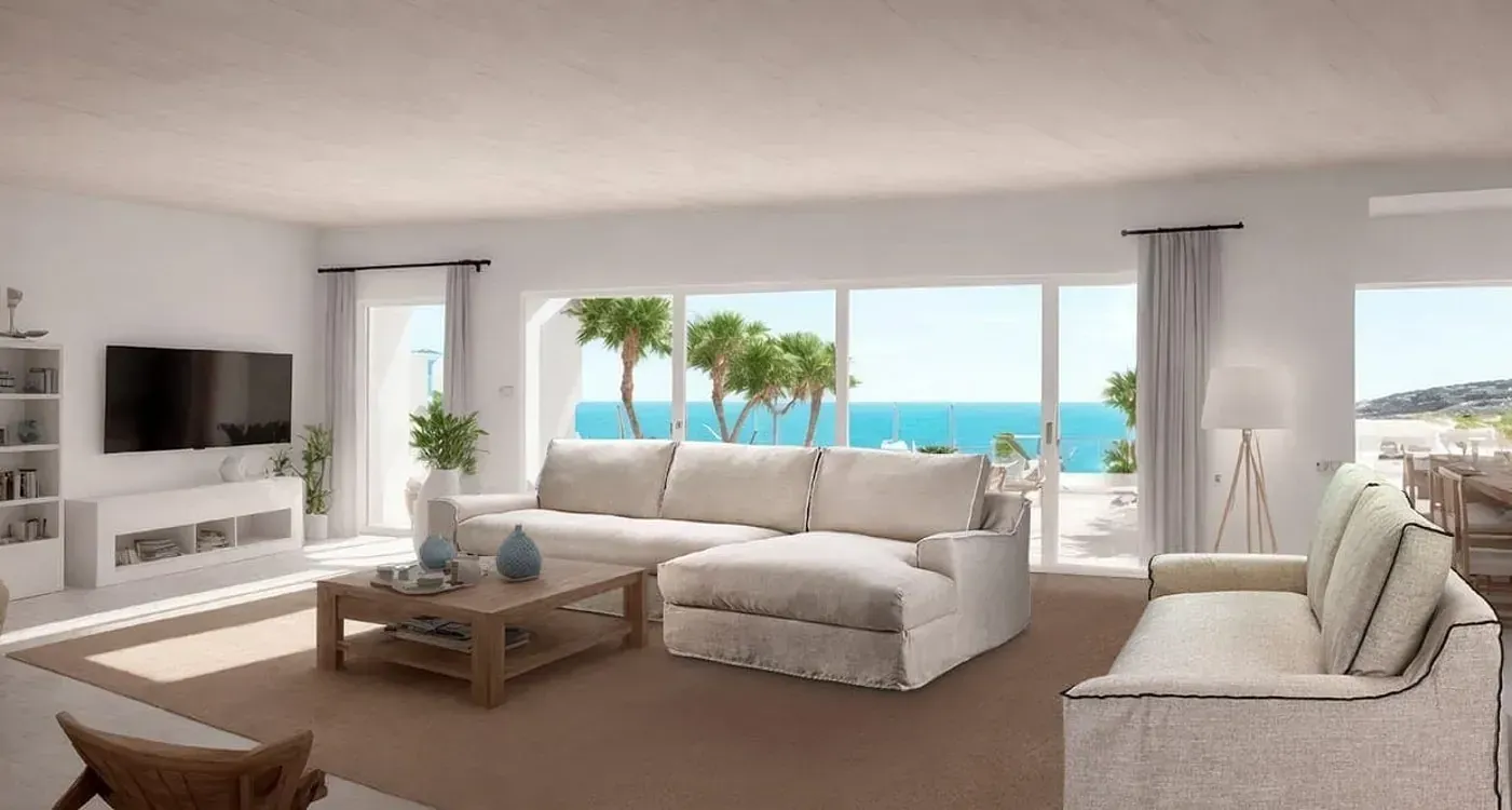 Una sala de estar con sofá, mesa de café, televisión y vista al mar.