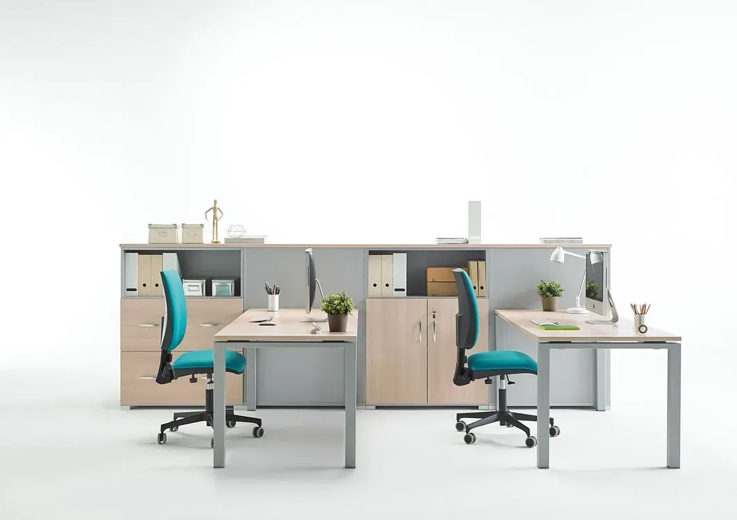 Una fila de escritorios y sillas en una oficina con un fondo blanco.