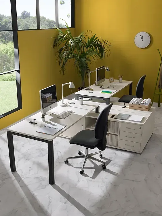 Una habitación con tres escritorios y sillas y un reloj en la pared.