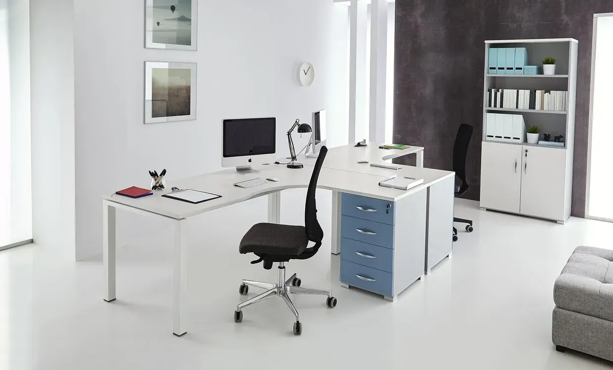 Un escritorio blanco con una silla negra y una computadora encima.