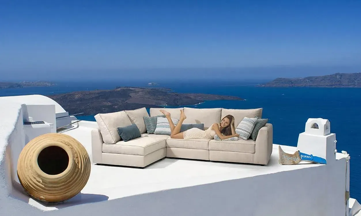 Una mujer está acostada en un sofá en un tejado con vistas al océano.