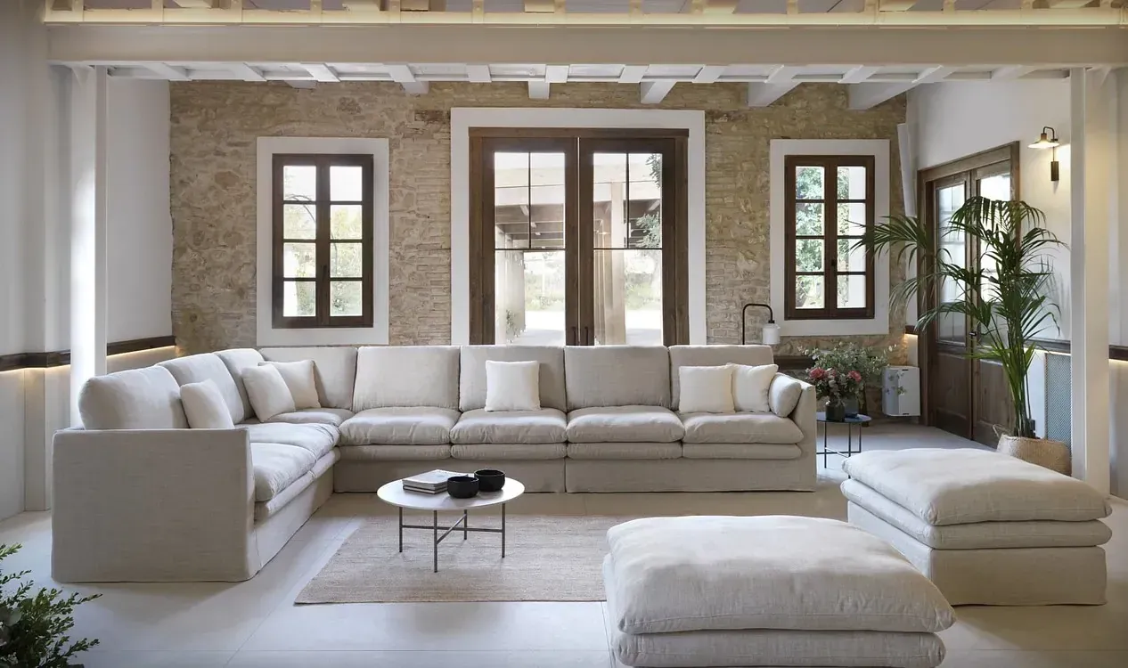 Una sala de estar con un gran sofá seccional y otomanas.