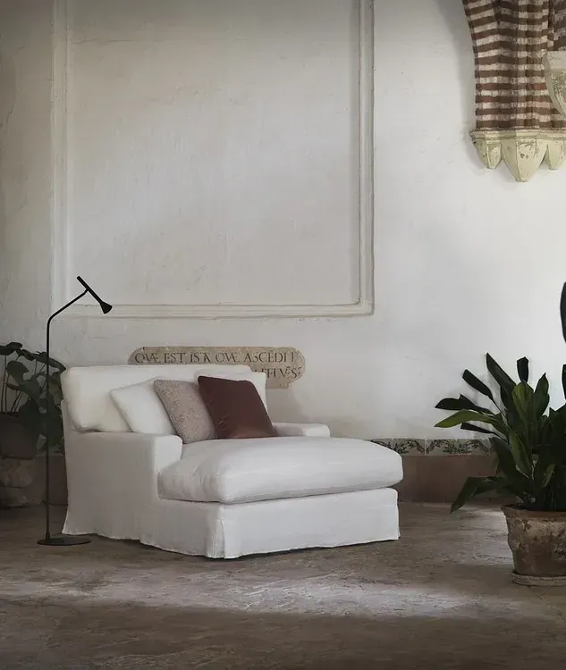 Una silla blanca en una sala de estar con una placa en la pared que dice 'auctor'.