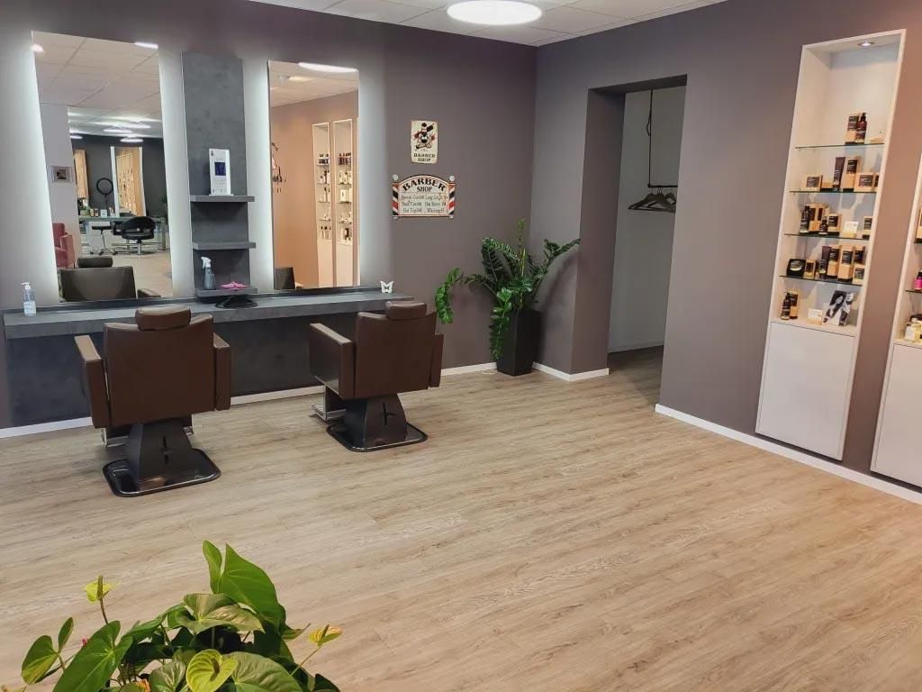 Ein Salon mit zwei Stühlen und einer Pflanze auf dem Boden