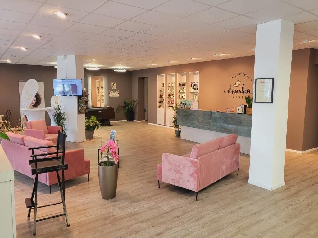 Ein großer Raum mit einer rosa Couch und Stühlen