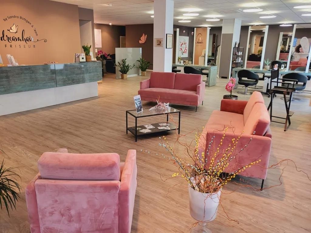 Ein Salon mit einer rosa Couch und rosa Stühlen