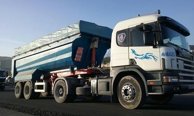 Un camión volquete blanco y azul está estacionado al costado de la carretera.