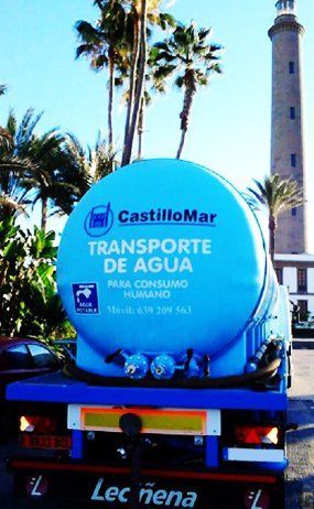 Un camión azul de Castillomar está estacionado frente a un faro.