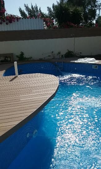 Una gran piscina azul con terraza de madera.