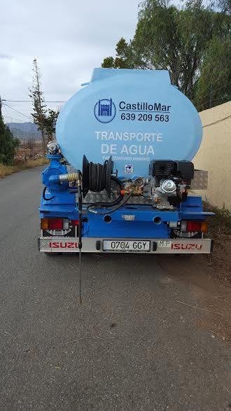 Un camión de agua azul está estacionado al costado de la carretera.
