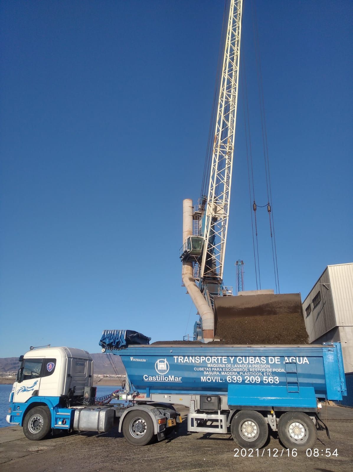 Un camión con una grúa acoplada está estacionado en un estacionamiento.