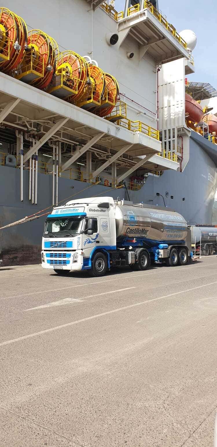 Un camión está estacionado frente a un gran barco.