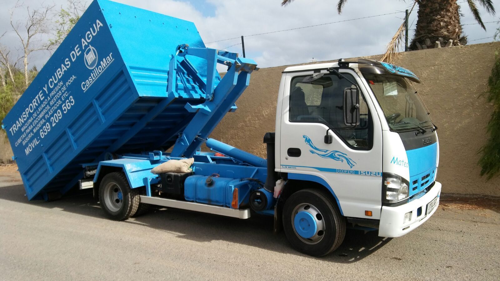Un camión volquete azul y blanco está estacionado al costado de la carretera.