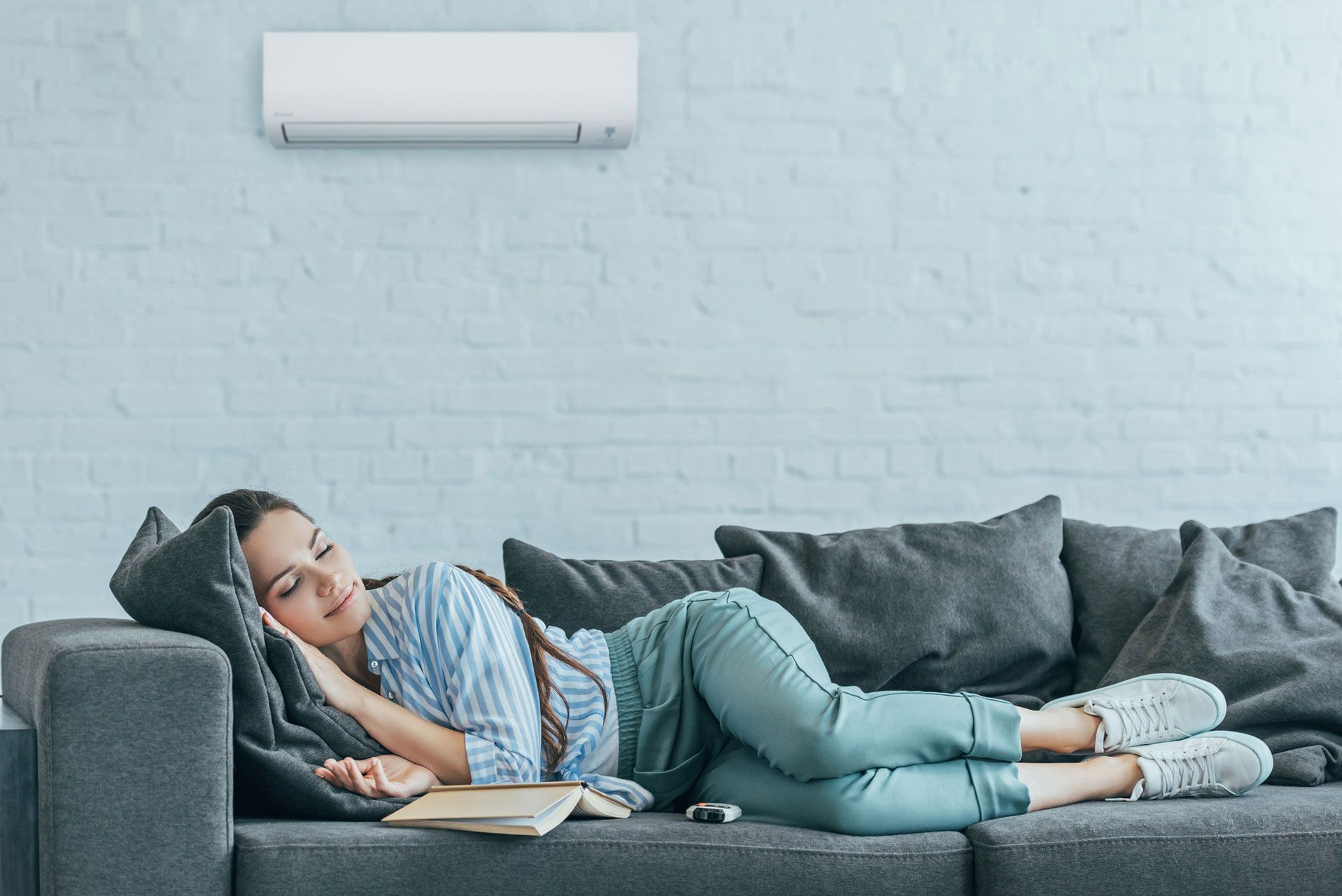 Femme sur un canapé avec un climatiseur au-dessus d'elle