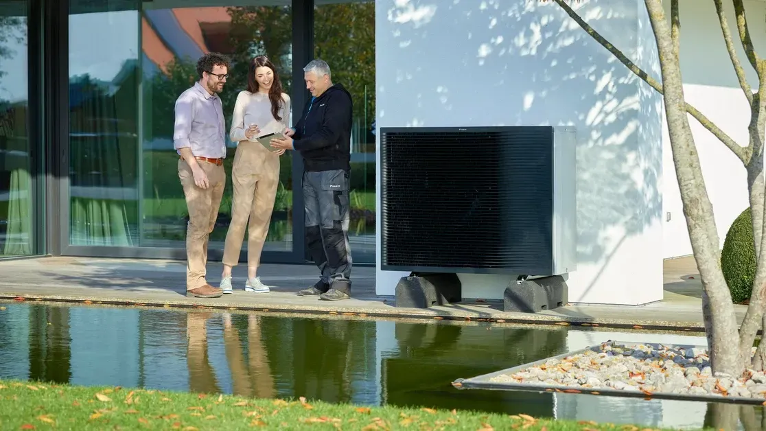 Un couple et un installateur devant une PAC air/eau
