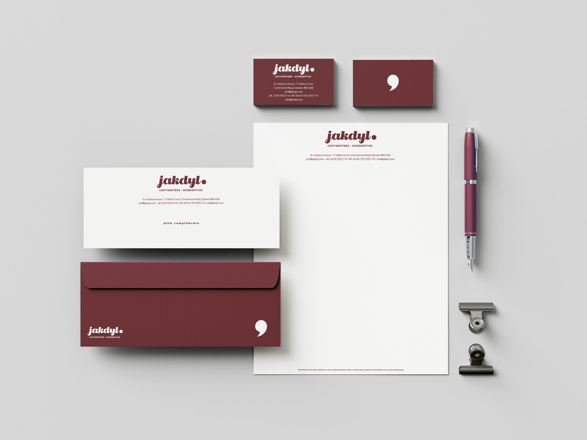 A branding stationery set on a light gray background, featuring business cards, letterhead, an envelope, a pen, and clips.