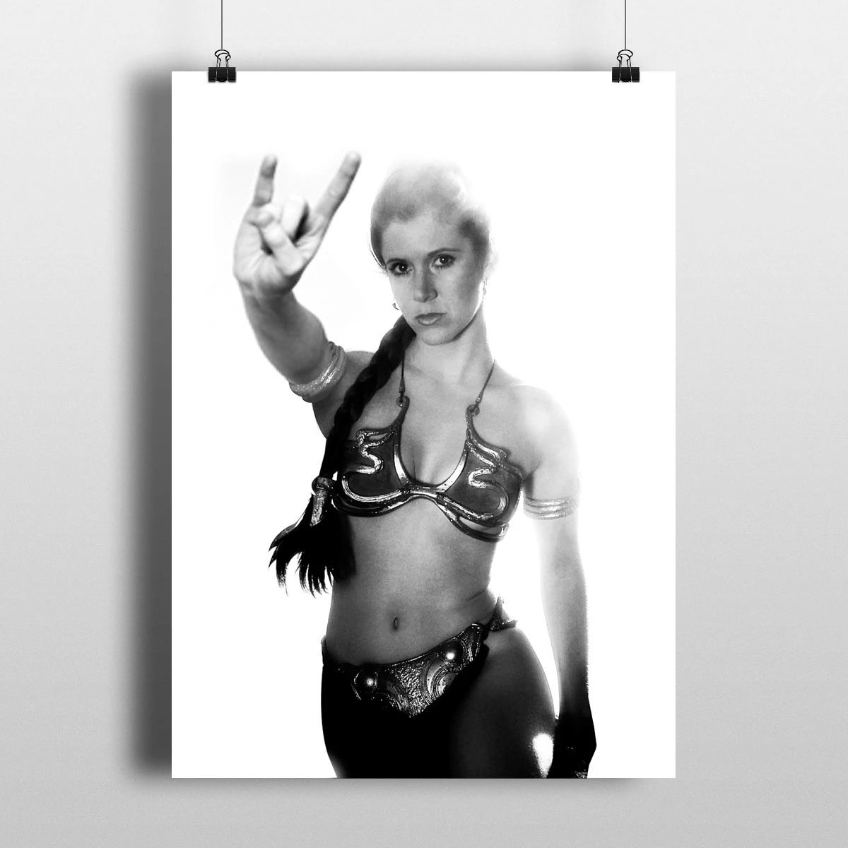 A black and white portrait of a person in a metal bikini costume making a rock-and-roll hand gesture.