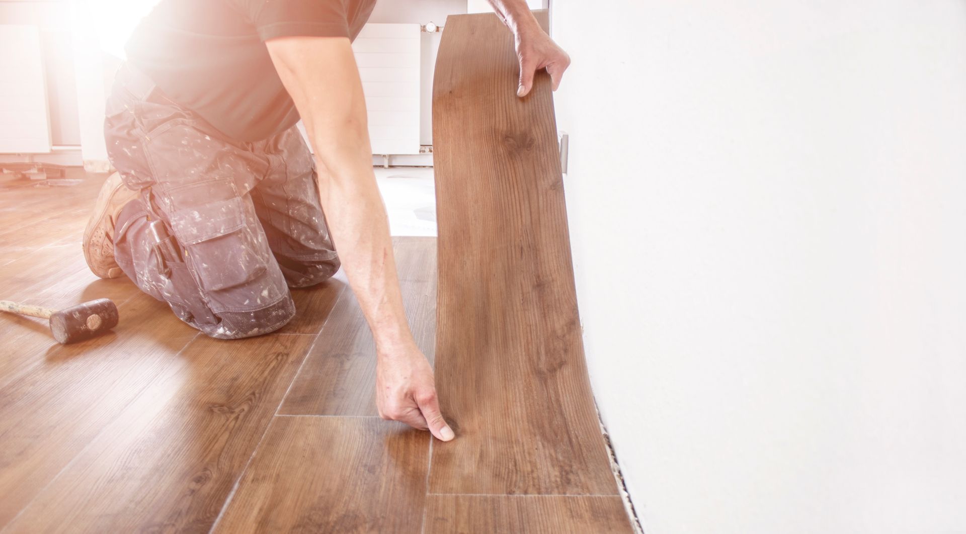 Mains qui installent un bloc de parquet en bois au sol