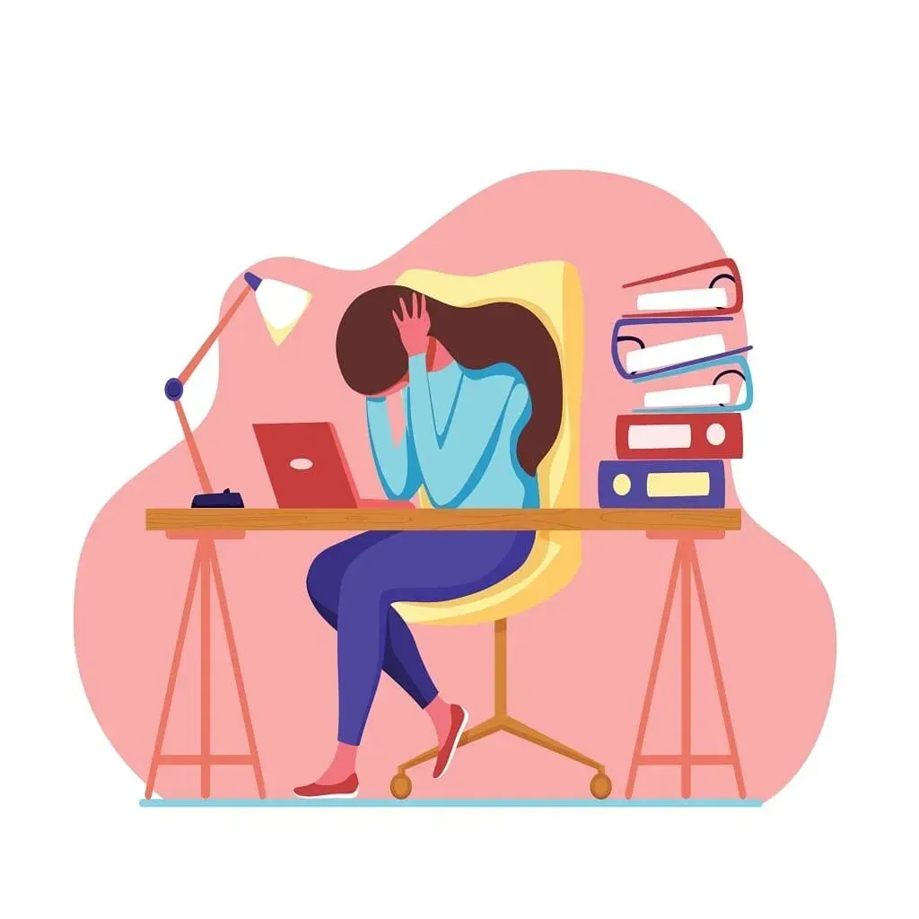 Una mujer está sentada en un escritorio con las manos en la cara.