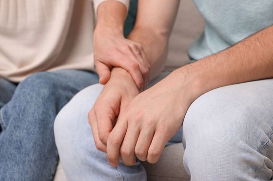 Un hombre y una mujer se toman de la mano mientras están sentados en un sofá.