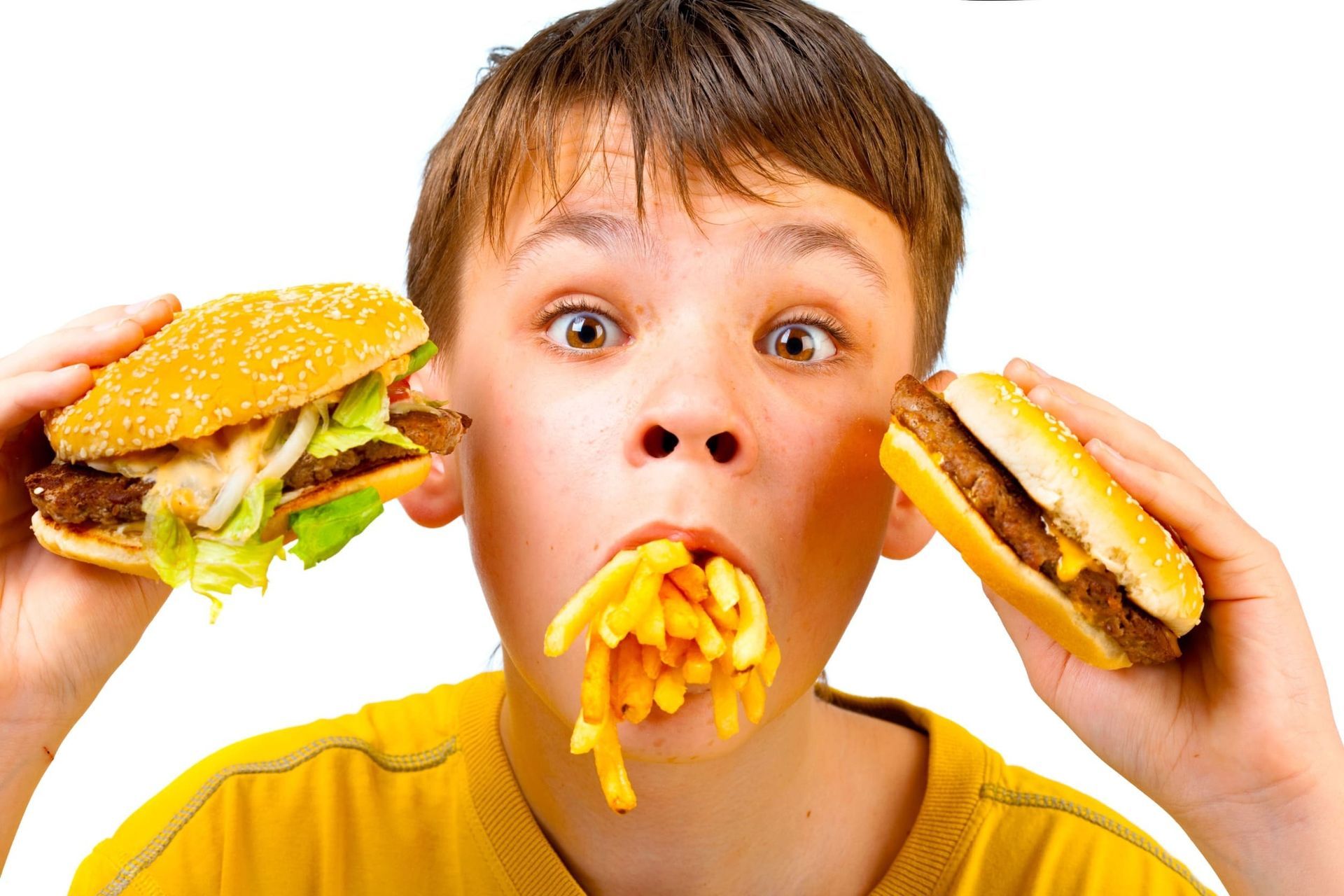 Un niño pequeño está comiendo una hamburguesa y papas fritas