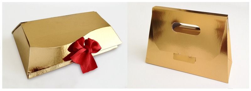 Una caja dorada con una cinta roja y una bolsa dorada con asa.