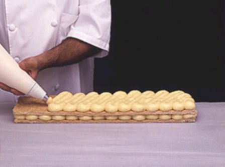 Un chef está glaseando un pastel con una manga pastelera.
