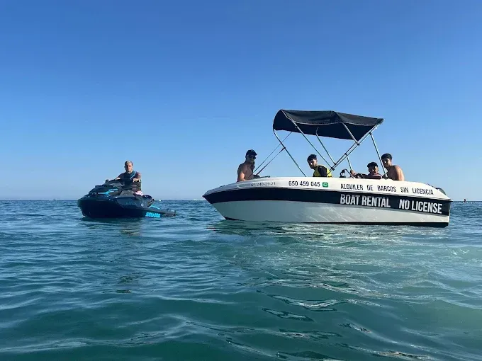 Un grupo de personas viajan en un bote en el océano junto a una moto acuática.