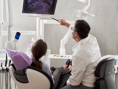 Un dentista utiliza un espejo dental y un instrumento para examinar de cerca los dientes de un paciente.