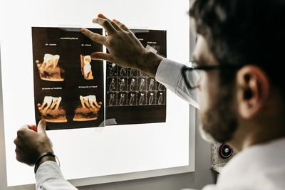 Un dentista utiliza un espejo dental y un instrumento para examinar de cerca los dientes de un paciente.