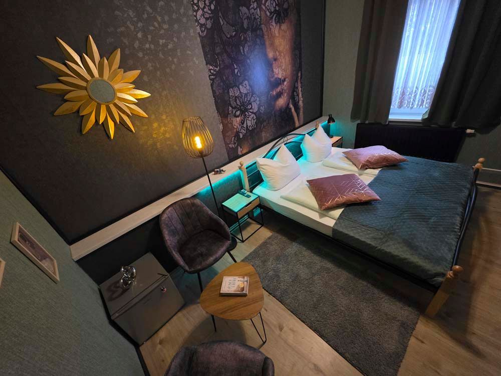 Ein Schlafzimmer mit einem Bett, Stühlen, einem Tisch und einem Gemälde an der Wand.