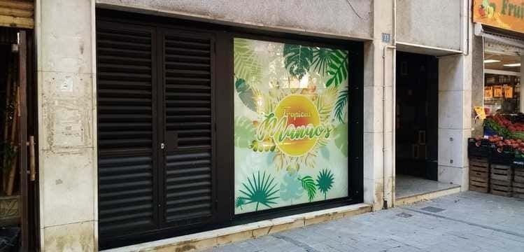 Un escaparate con una ventana con una imagen de un sol y palmeras.