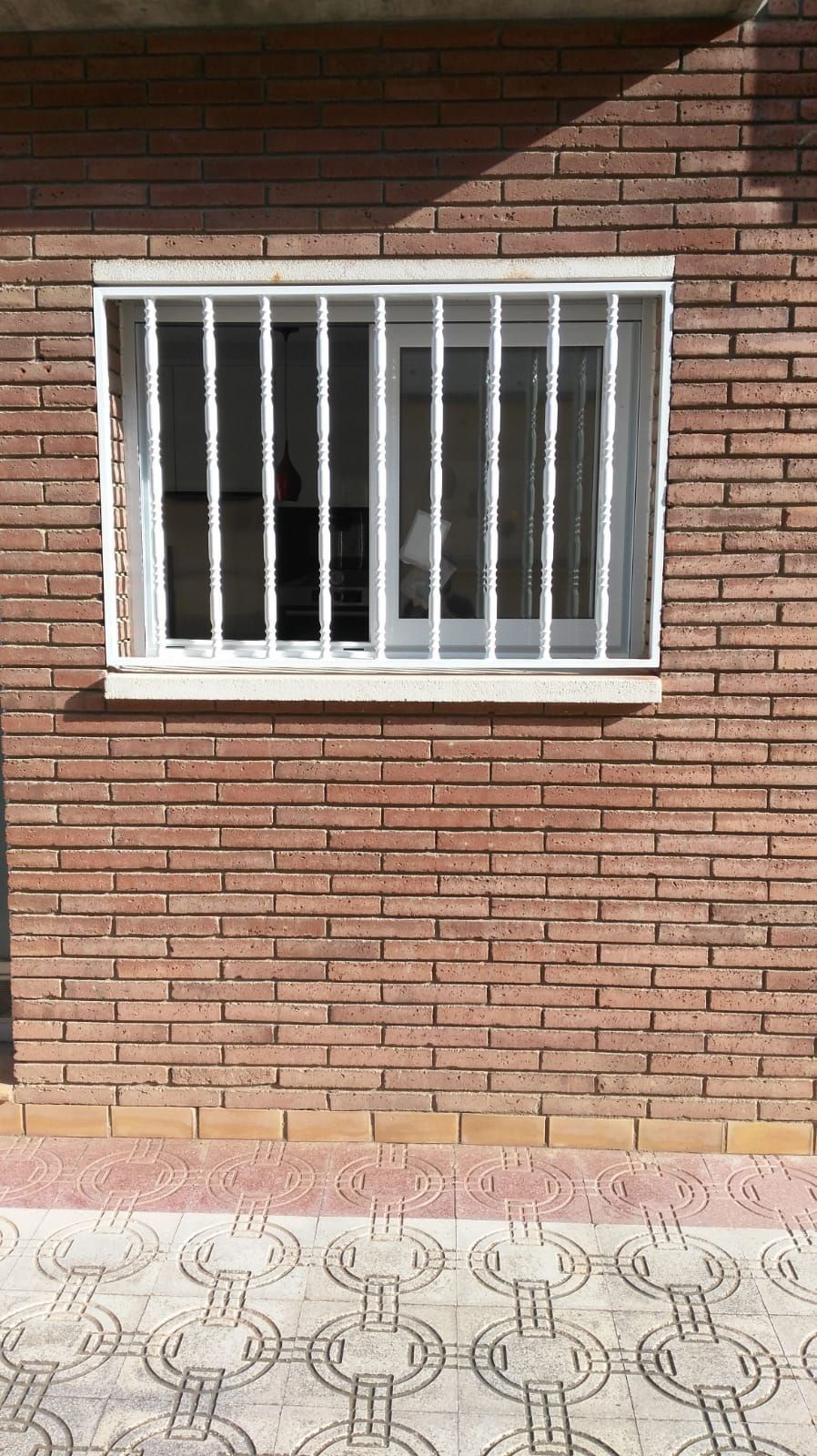 Una pared de ladrillos con una ventana con rejas.