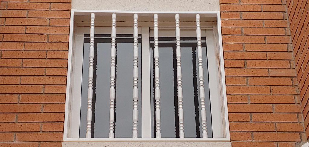 Un edificio de ladrillo con una ventana con barandilla blanca.