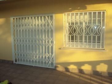 Un edificio amarillo con una puerta blanca y una ventana con rejas.