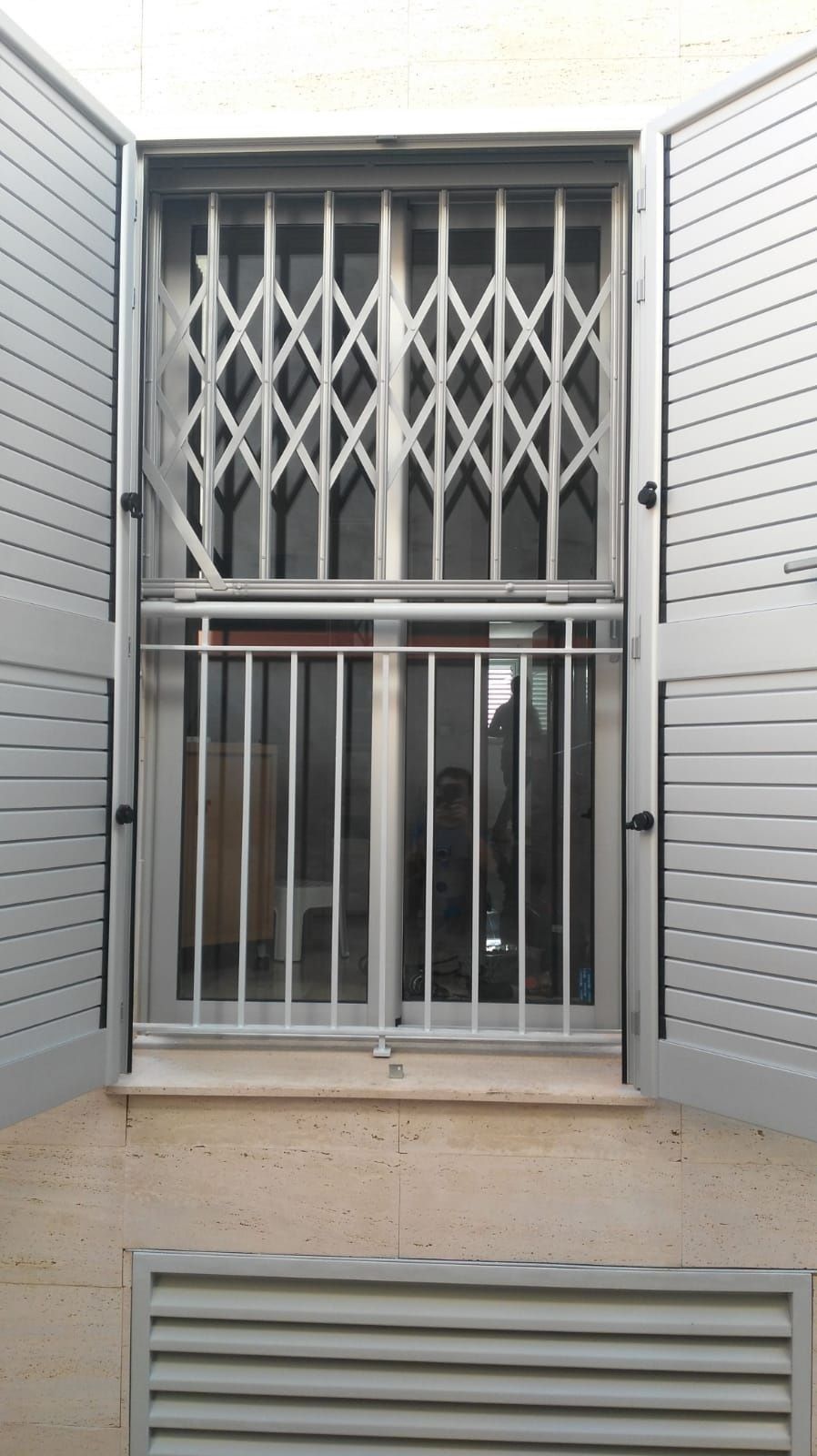 Una ventana con una puerta de metal y contraventanas.