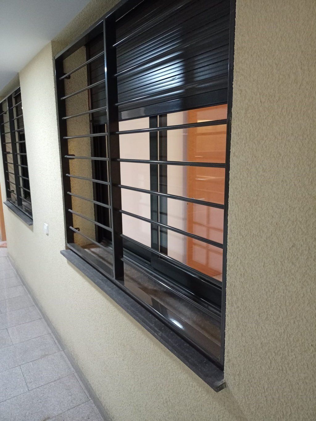Un pasillo con dos ventanas con rejas.