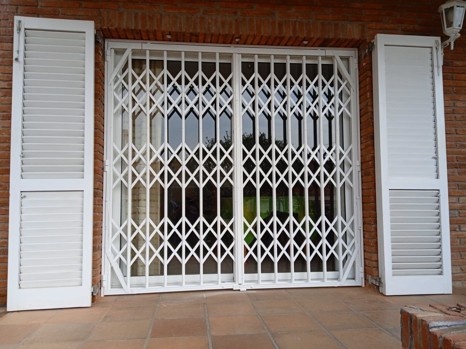 Un edificio de ladrillo con contraventanas blancas y una puerta blanca.