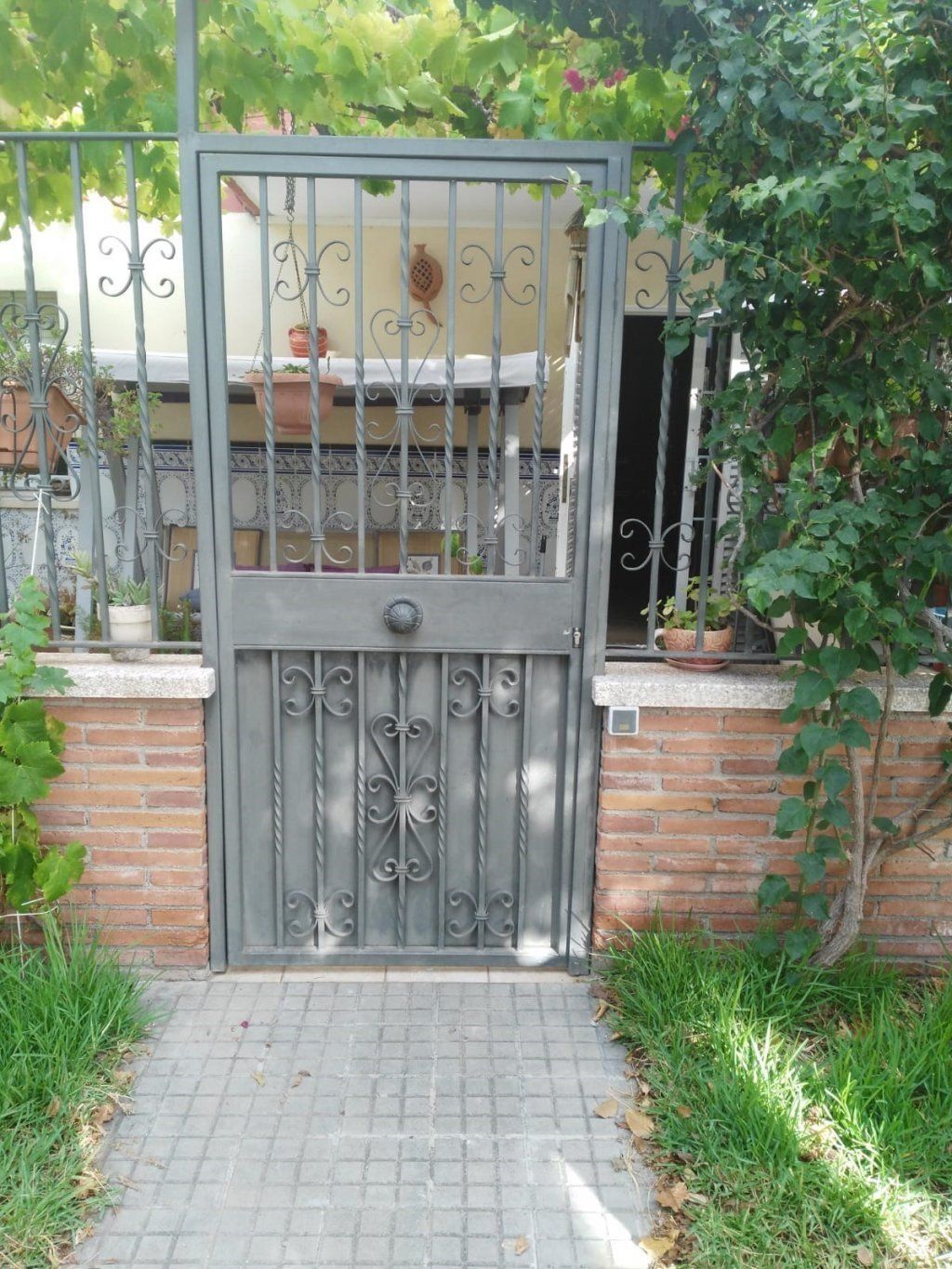 Una puerta de hierro forjado con una pared de ladrillos detrás de ella.