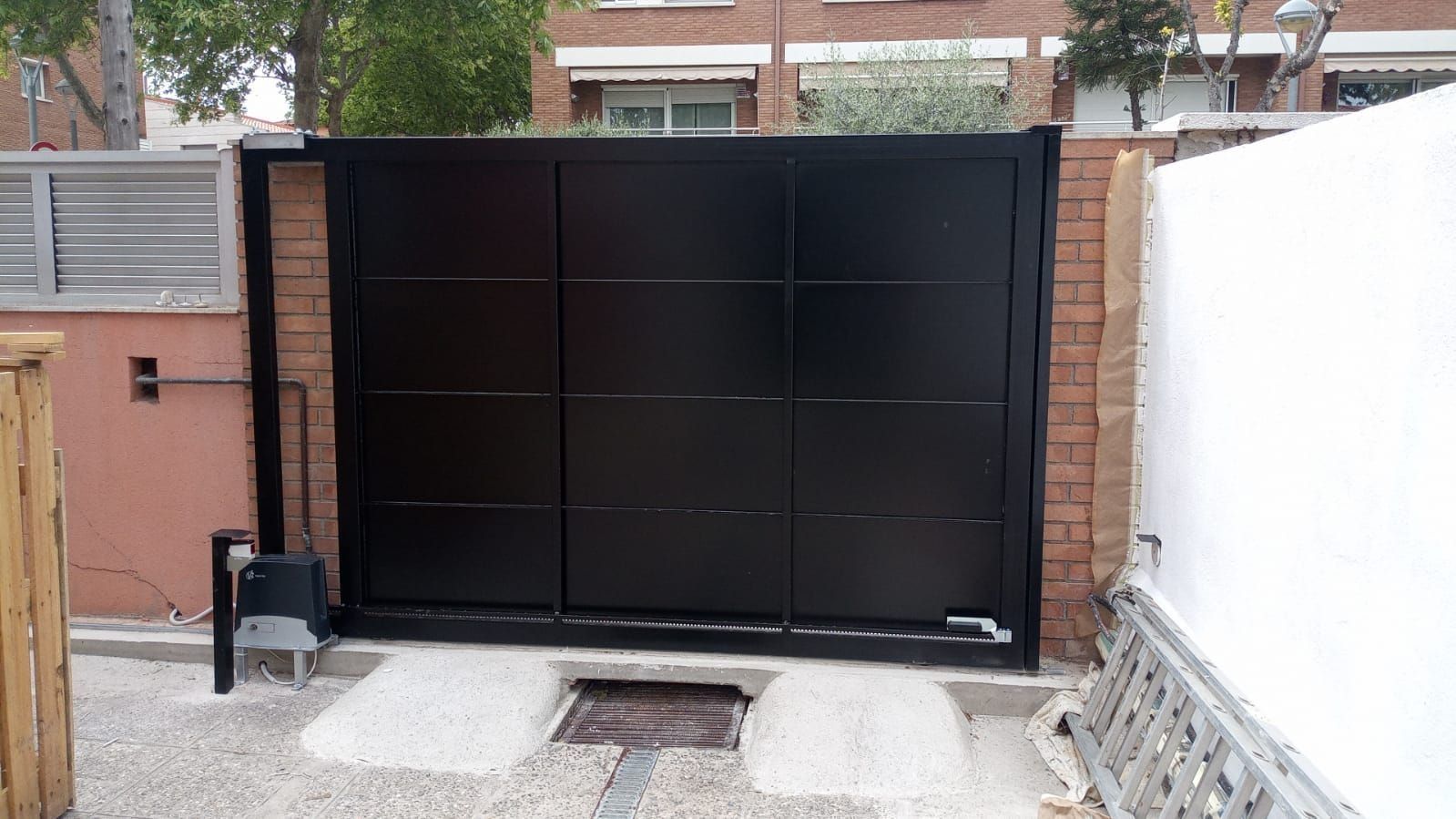 Una puerta negra está delante de una pared de ladrillos.