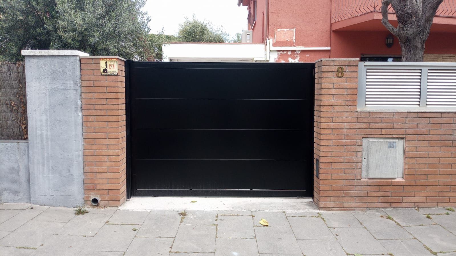 Una pared de ladrillos con una puerta negra delante.