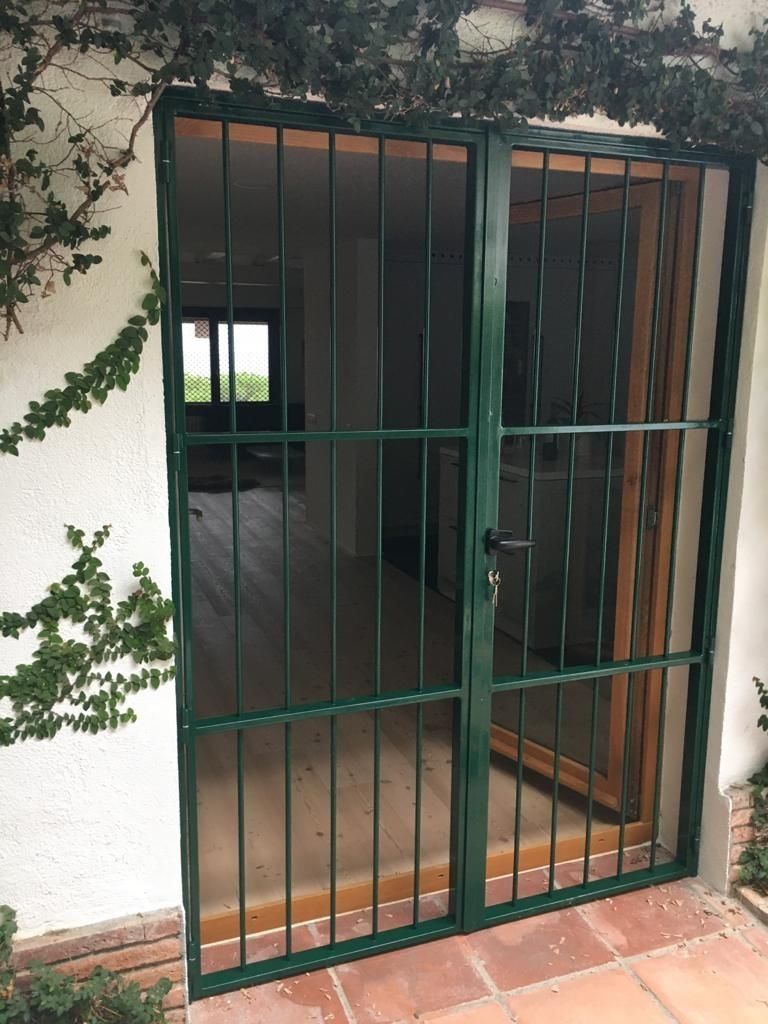 Una puerta verde con rejas da a una habitación.