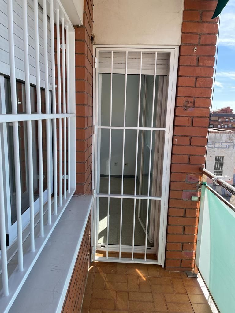 Un balcón con una pared de ladrillo y una puerta blanca.