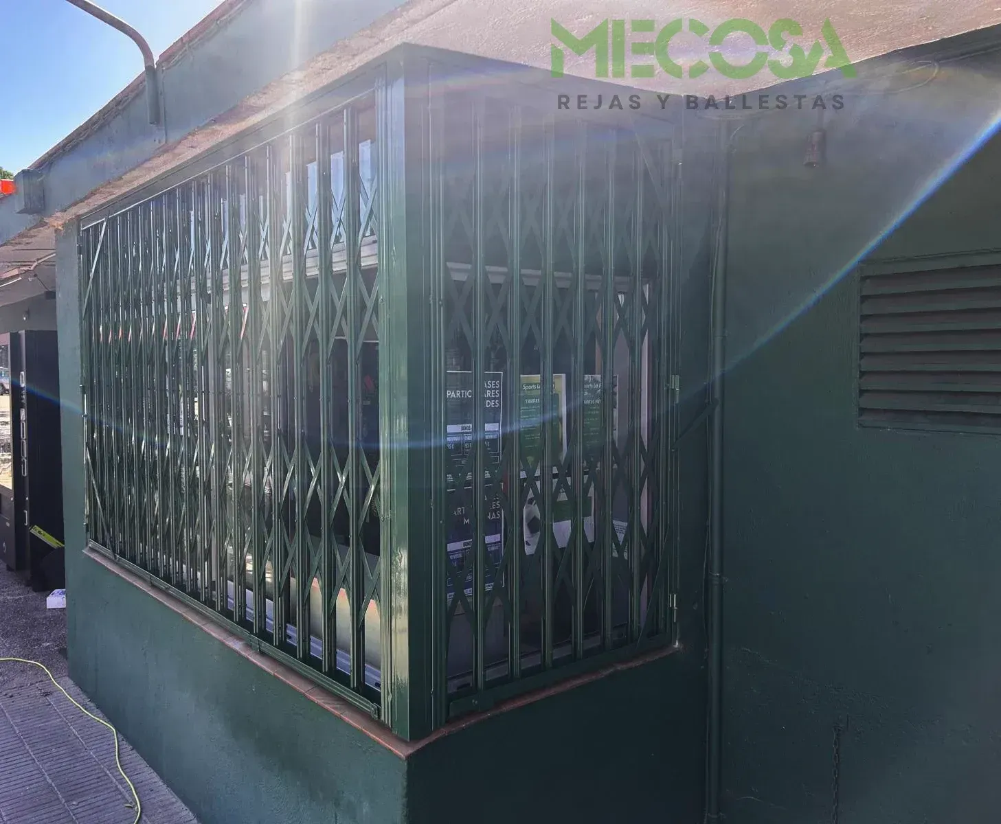 Un edificio verde con una valla metálica en el lateral.